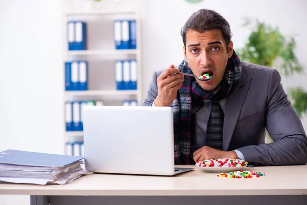 Jonge mannelijke werknemer die op het werk lijdt — Stockfoto