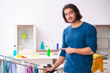 Genç adam evde çamaşır ütülüyor.