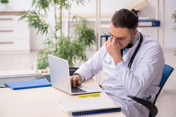 Klinikte çalışan genç erkek doktor.