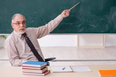 Sınıftaki yaşlı erkek öğretmen.