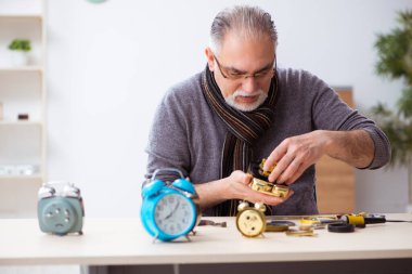 Atölyede çalışan yaşlı bir erkek saatçi.