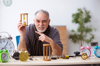 Atölyede çalışan yaşlı bir erkek saatçi.