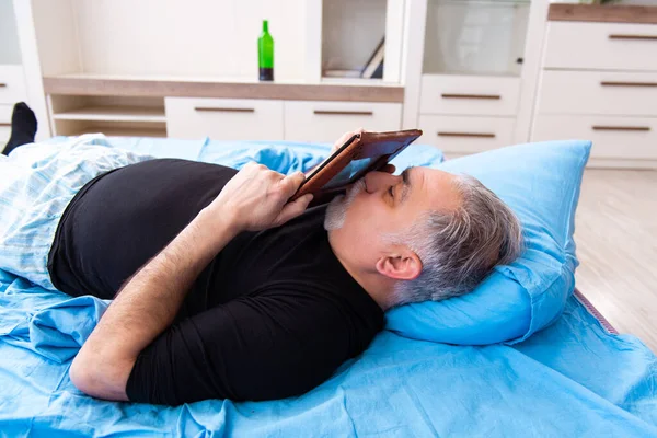 Alter Mann trinkt Wein im Schlafzimmer — Stockfoto