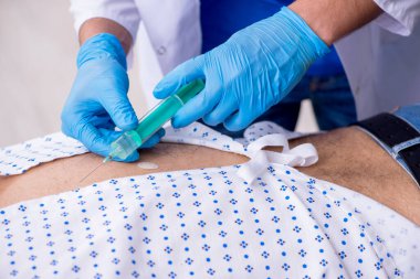 Yaşlı adam genç erkek stajyer doktoru ziyaret ediyor.