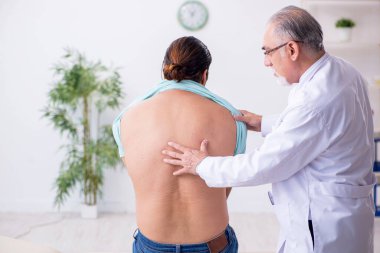 Genç sırtı yaralı adam deneyimli erkek doktoru ziyaret ediyor.