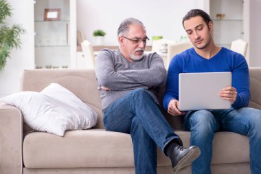 Baba oğul kanepede bilgisayar başında oturuyor.