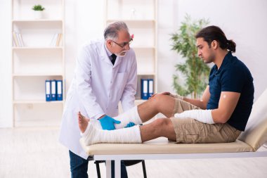 Genç yaralı adam yaşlı doktor travmatoloğu ziyaret ediyor.