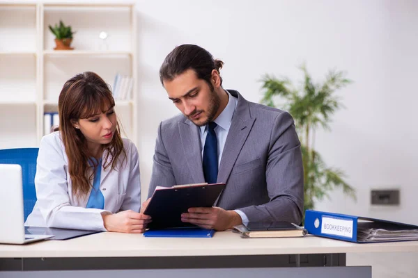 Junge Ärztin und kranker Geschäftsmann im Büro — Stockfoto