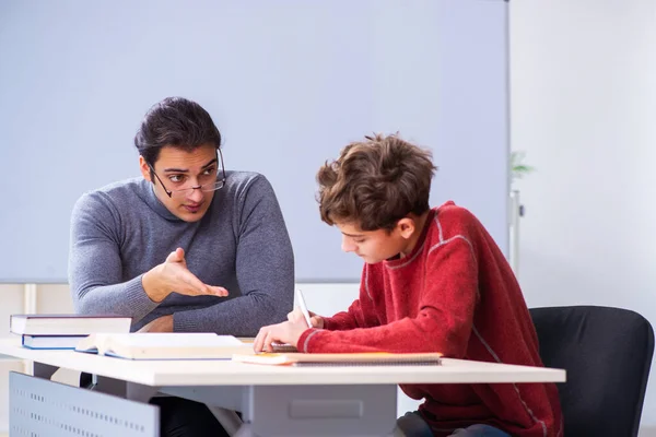 Jeune enseignant et écolier dans la salle de classe — Photo