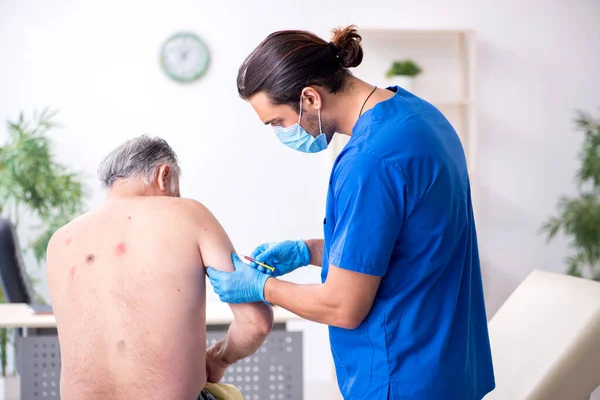 Starý muž návštěva mladý lékař dermatolog — Stock fotografie