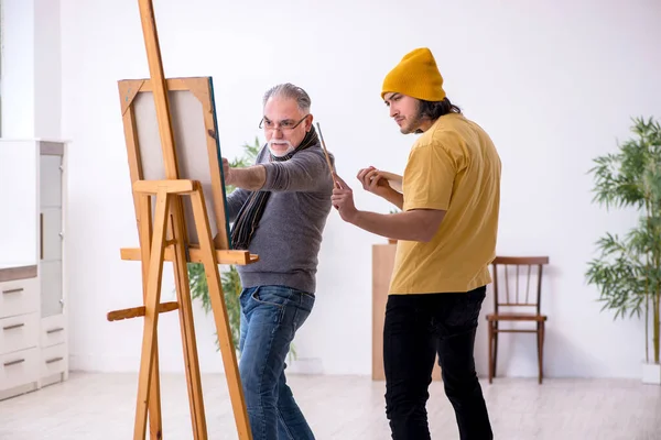 Старик берет уроки у молодого художника — стоковое фото