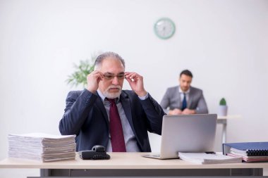 Eski patron ve genç asistanı ofiste çalışıyor.