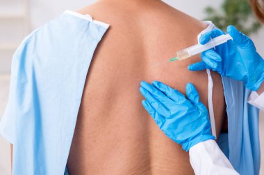 Genç sırtı yaralı bir adam, kadın doktor masörünü ziyaret ediyor.