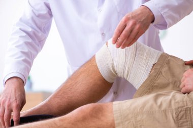 Deneyimli doktor travmatolog genç erkek hastayı muayene ediyor.