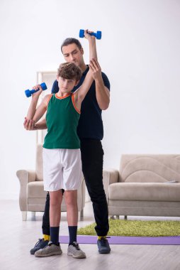 Baba ve oğul içeride spor yapıyor.