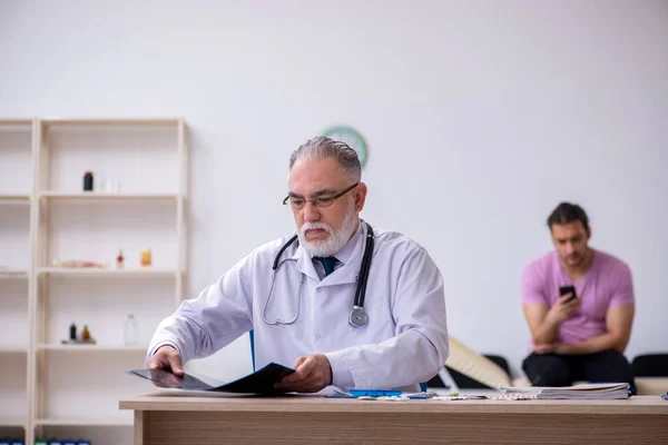 Old doctor radiologist examining young male patient