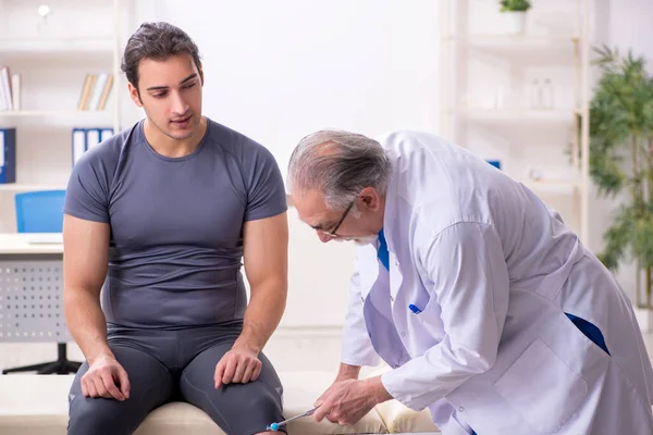 Young male patient visiting old doctor traumatologist — Stock Photo, Image