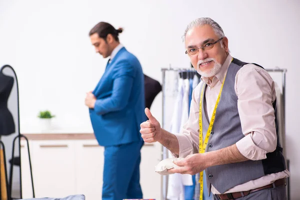 Jonge zakenman op bezoek bij oude mannelijke kleermaker — Stockfoto