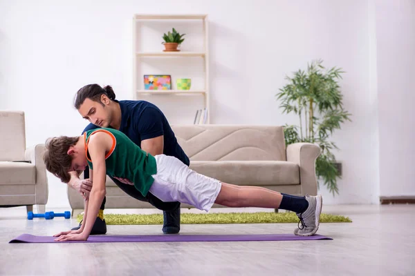 Pai e filho fazendo exercícios esportivos dentro de casa — Fotografia de Stock