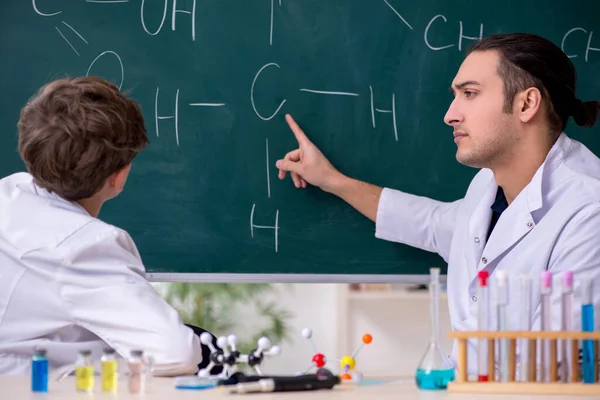 Young chemistry teacher and schoolboy in the classroom — Stock Photo, Image