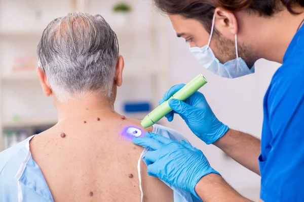 Alter Mann besucht jungen männlichen Arzt Dermatologen — Stockfoto
