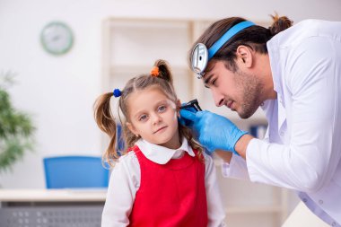 Küçük kız, genç erkek doktor otorhinolaryngologist 'i ziyaret ediyor.