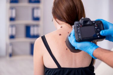 Genç bir kadın erkek doktor dermatoloğunu ziyaret ediyor.