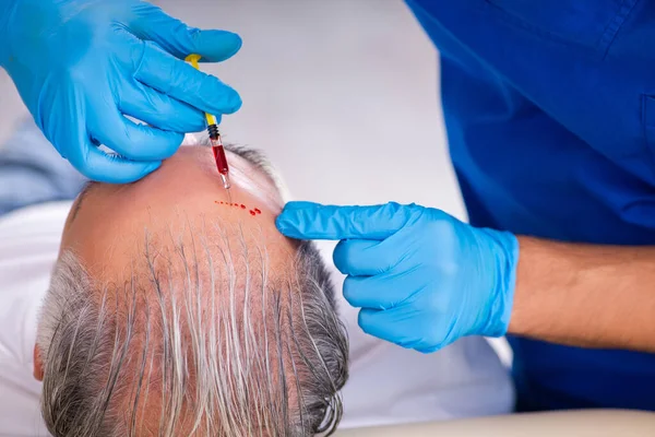 Old man visiting young male doctor in hair transplantation conce — Stock Photo, Image