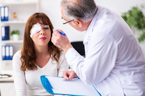 Giovane donna in visita vecchio medico oftalmologo — Foto Stock