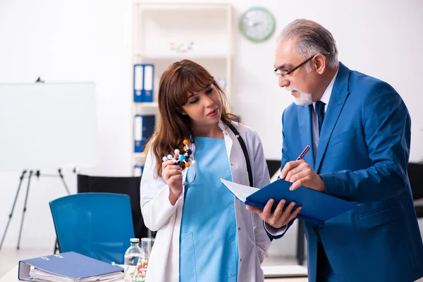 Gammal affärsman besöker ung kvinnlig läkare — Stockfoto