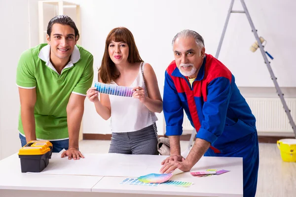 Young couple and old contractor in home renovation concept — Stock Photo, Image