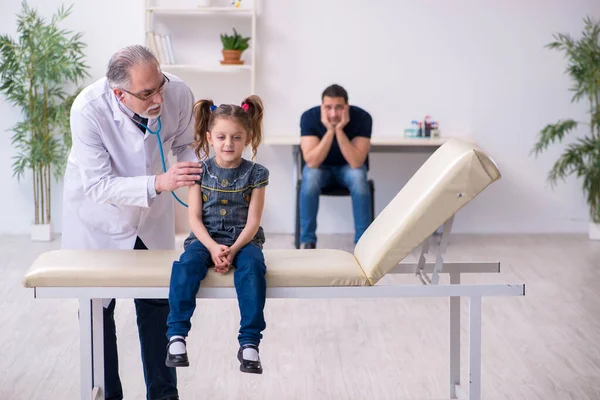 Jovem pai e sua filha visitando velho médico masculino — Fotografia de Stock