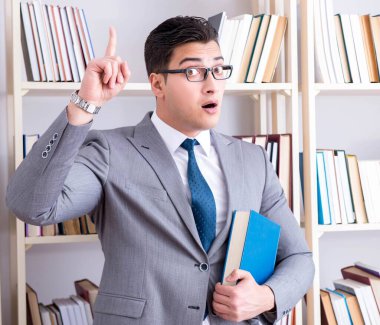 İş adamı öğrenci kütüphanede okuyan bir kitap okuyor.