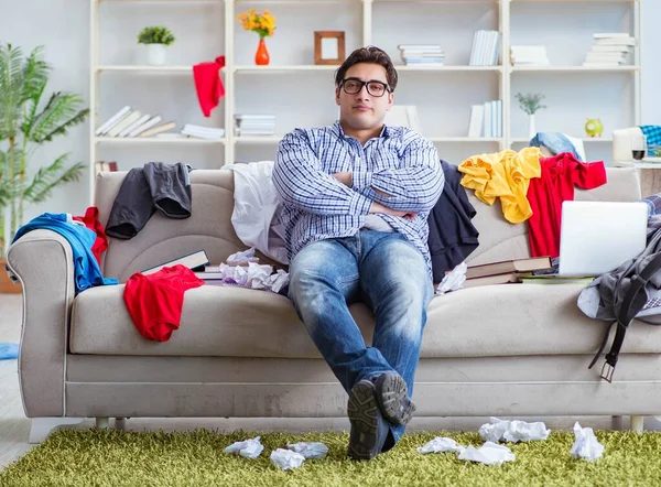 Dağınık odada çalışan genç adam.