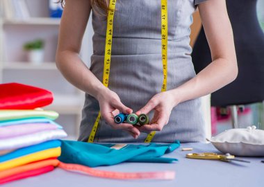 Kadın terzi dikiş dikmek için dikiş dikiyor.