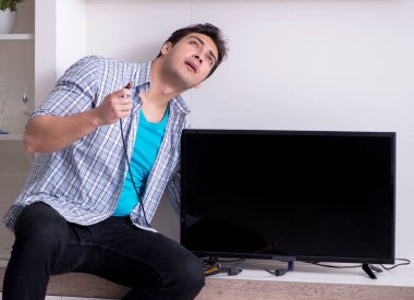 Bozuk televizyonu tamir etmeye çalışan adam