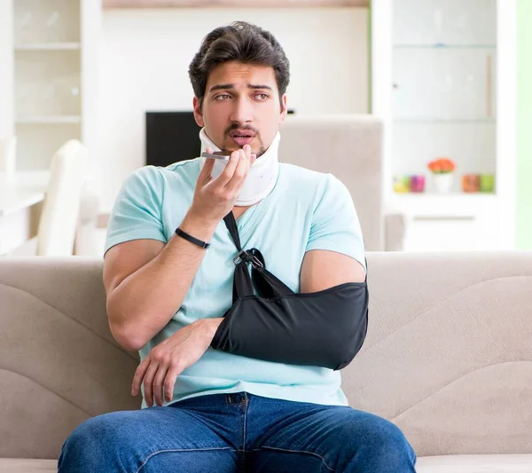 Joven estudiante con lesión en el cuello y la mano sentado en el sofá — Foto de Stock