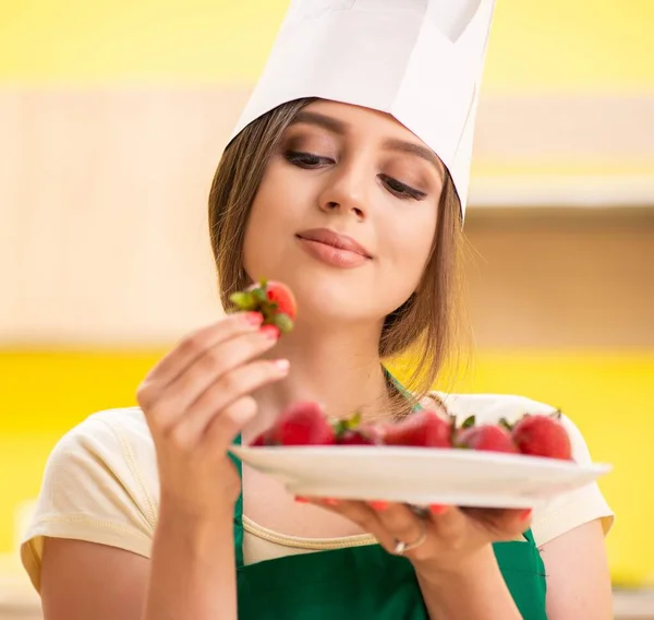 Νεαρή μαγείρισσα τρώει φράουλες — Φωτογραφία Αρχείου