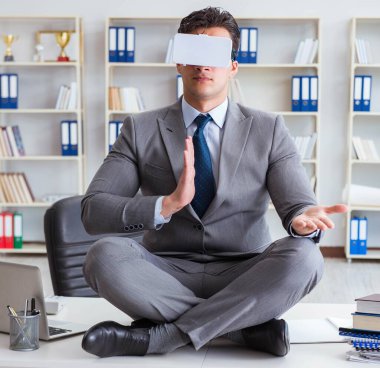 Sanal gerçeklikteki iş adamı VR gözlükleri masanın üstünde meditasyon yapıyor.