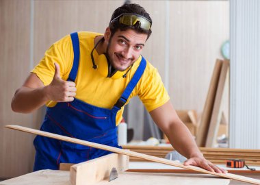 Genç tamirci marangoz odun kesiyor.