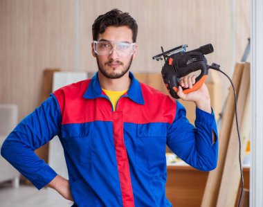 Elektrikli testereyle çalışan genç tamirci.