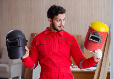 Kaynak tabancası elektrot ve kask takan genç bir tamirci.