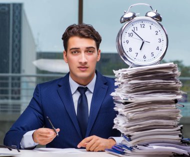 Yığınla evrak işi ve alarm sistemi olan bir iş adamı.