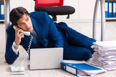 Yorgun iş adamı ofiste fazla mesai yapıyor.