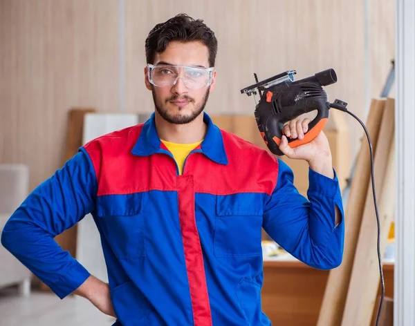 Elektrikli testereyle çalışan genç tamirci.