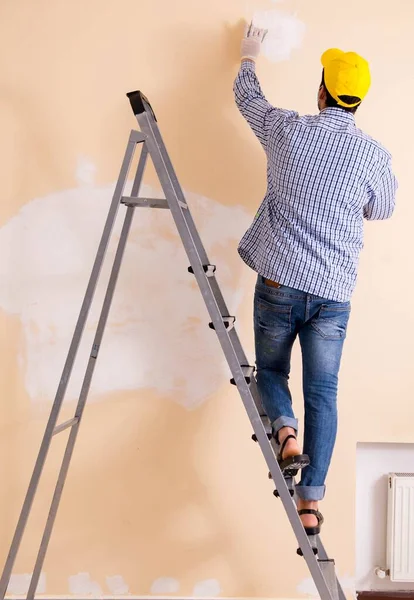 Contratista joven lijando pared con papel de lija — Foto de Stock