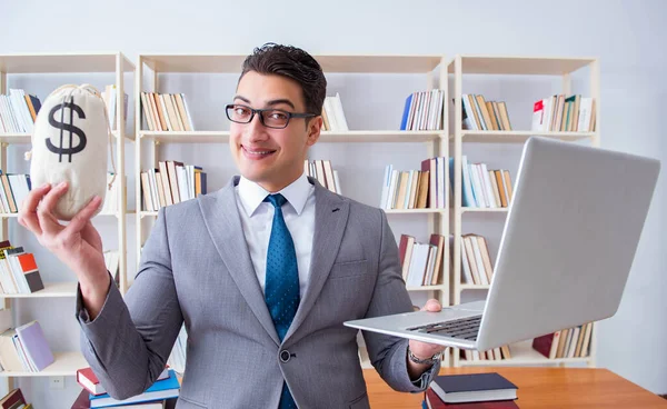 Affärsman i biblioteket med en pengasäck och en laptop — Stockfoto