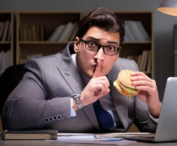 Homme d'affaires tard dans la nuit manger un hamburger — Photo