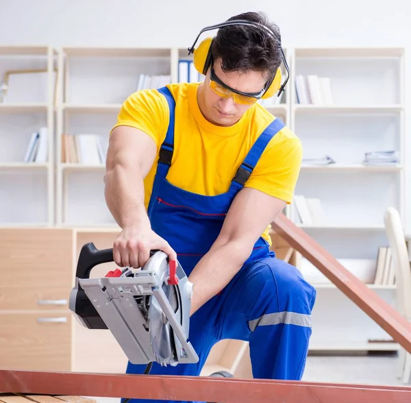 Reparador carpintero cortando aserrar una tabla de madera con un circuito —  Fotos de Stock