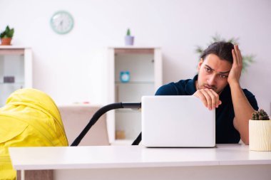 Genç baba yeni doğan bebeğe bakıyor.